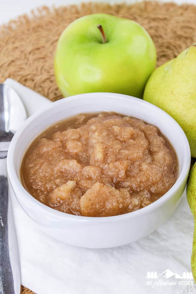 Bowl of homemade apple pear sauce surrounded by fresh apples and pears.