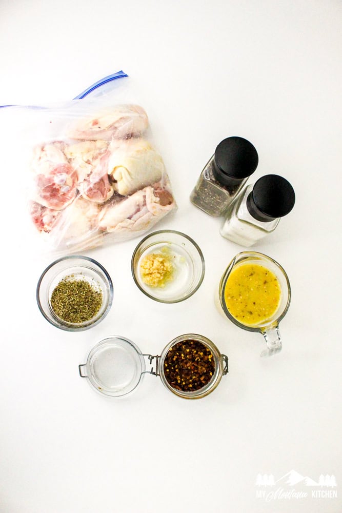 Overhead view of ingredients for Italian baked chicken thighs, including garlic, herbs, and dressing.