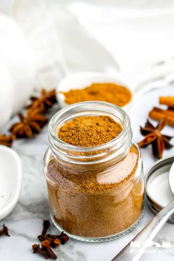 Overhead shot of a jar filled with homemade pumpkin pie spice, surrounded by fall spices and decor