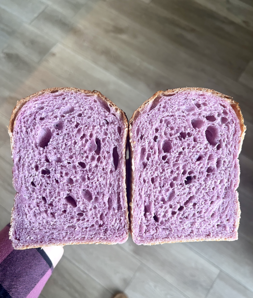Valentine’s Day sourdough sandwich bread cut in half, showing airy pink purple crumb from naturally colored ube sourdough bread
