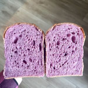 Valentine’s Day sourdough sandwich bread cut in half, showing airy pink purple crumb from naturally colored ube sourdough bread