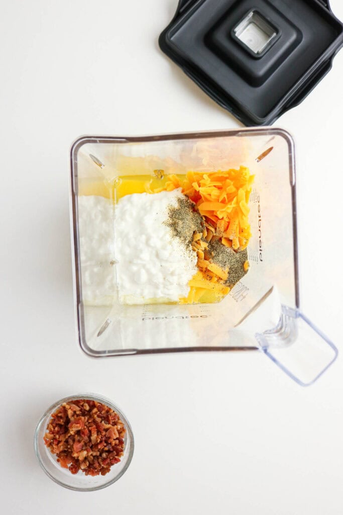 Eggs, cottage cheese, cheddar, and seasonings in blender for egg bite recipe.