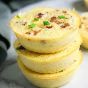 Stacked cottage cheese egg bites with bacon and chives, showing fluffy texture and golden edges.