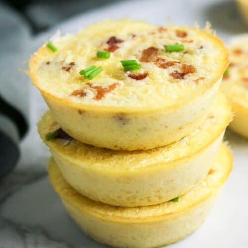 Stacked cottage cheese egg bites with bacon and chives, showing fluffy texture and golden edges.